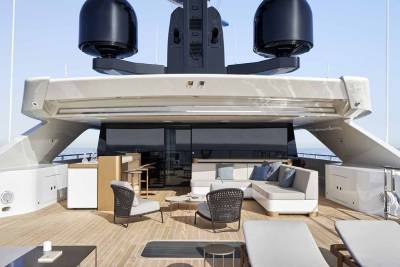 Luxurious outdoor lounge areas on a modern yacht offer comfortable seating and elegant design against a backdrop of the open sea.
