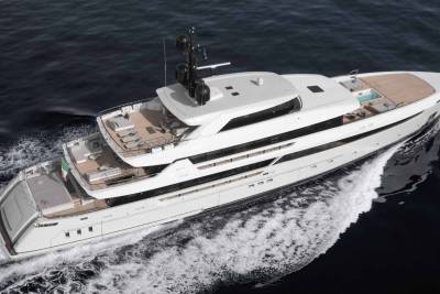 A sleek white superyacht glides through dark blue waters, leaving a foamy wake.