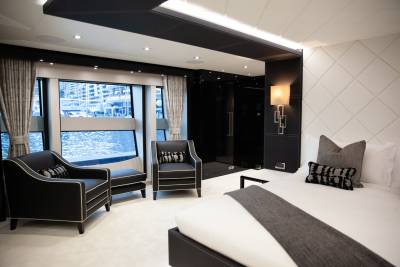 Luxurious yacht interiors feature plush seating and a comfortable bed with a view of the marina.
