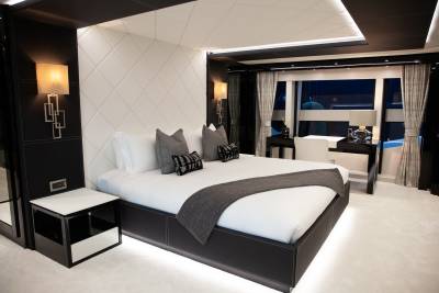 Luxurious yacht master suite features a plush bed, elegant wall sconces, and a sleek desk overlooking the water.