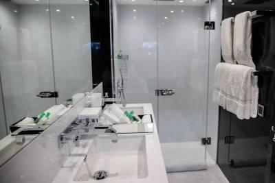 A modern bathroom features a sleek double vanity with chrome fixtures and a glass-enclosed shower with fluffy white towels.