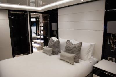 Luxurious yacht master suite features a plush king-sized bed and elegant upholstered headboard with access to a private staircase.