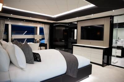 Luxurious yacht interiors feature a sleek bedroom with a large window overlooking the dark sea.