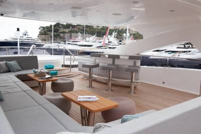 Luxurious yacht deck seating and bar area overlooks a harbor filled with impressive vessels.