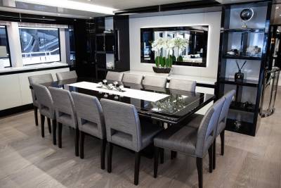 Elegant dining chairs surround a sleek black table adorned with white orchids and glassware.