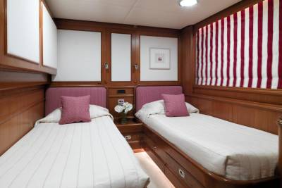 Twin beds with patterned headboards and crisp white linens offer a cozy retreat in this nautical-themed cabin.