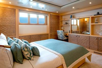 Luxurious yacht cabin offers a serene retreat with ocean views and elegant, textured wood finishes.