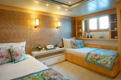 Two twin beds with coral-themed decor offer a serene nautical retreat in this luxurious cabin.
