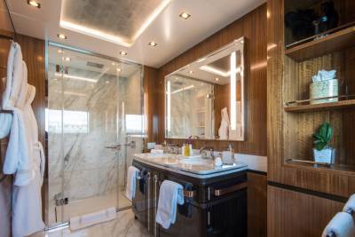 Luxurious marble and rich wood create a serene spa-like atmosphere in this elegant yacht bathroom.