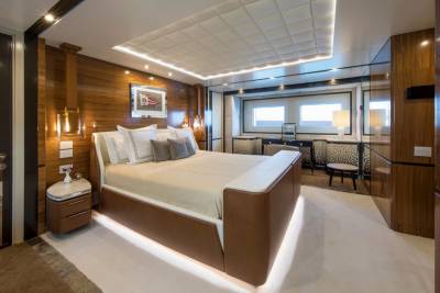 Luxurious yacht accommodations feature a plush king-size bed, elegant wood paneling, and ambient lighting for a serene retreat at sea.
