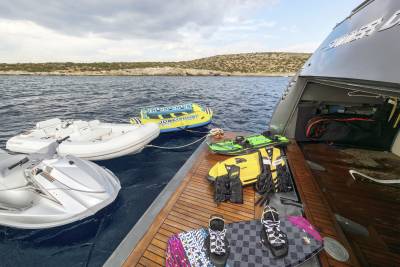 Ready for aquatic adventures, a yacht is loaded with jet skis, inflatable tubes, life vests, and wakeboards.