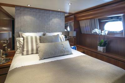 Luxurious yacht accommodations feature a plush bed with striped pillows and a serene ocean view.