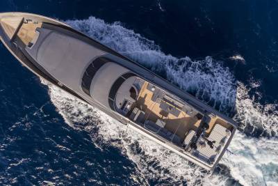 A sleek yacht glides through the deep blue ocean, leaving a trail of white foam in its wake.