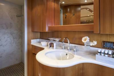 A luxurious yacht bathroom features a marble shower, elegant wooden cabinetry, and a sleek vanity with toiletries.