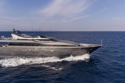 A sleek, modern yacht glides through the deep blue ocean under a clear sky.