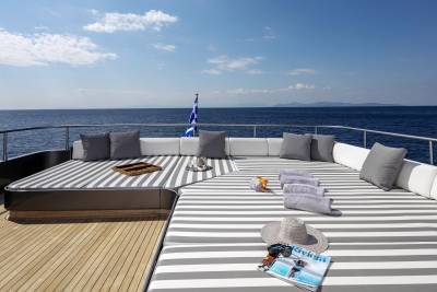 Relax on the striped deck of a yacht, surrounded by the tranquil blue sea and distant mountains.