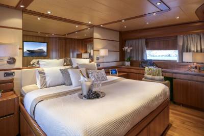 Luxurious yacht cabin awaits with a plush bed, chilled champagne, and a scenic view from the window.