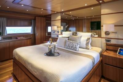 A luxurious yacht cabin awaits with a plush bed, chilled champagne, and a serene ocean view.