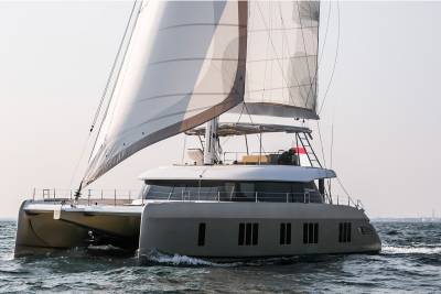 A sleek catamaran sails gracefully across the water under a bright sky, its sails catching the wind.