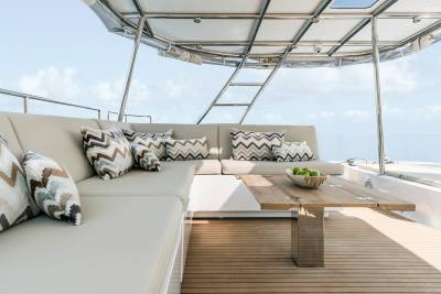 Relax on the plush seating of this luxury yacht's deck, complete with a wooden table and a bowl of fresh green apples.