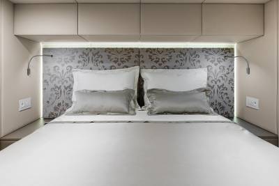 A modern bedroom features a plush bed with a patterned headboard and integrated lighting, creating a serene ambiance.