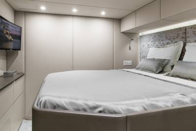Luxurious bedding and a mounted television create a serene and modern retreat aboard this elegant yacht.