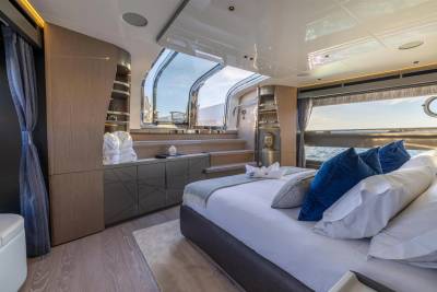 Luxurious yacht cabin features a comfortable bed with plush blue pillows and a stunning view of the ocean.