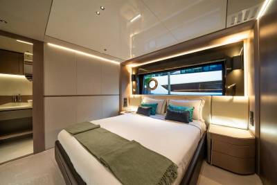 Luxurious yacht cabin features a comfortable bed, ambient lighting, and a porthole window offering a glimpse of the sea.