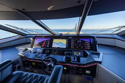 The modern yacht helm features multiple screens displaying navigation and engine data, offering a high-tech command center for the open sea.