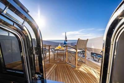 Enjoy a refreshing drink on the deck of this luxurious yacht as the sun shines brightly over the calm blue sea.