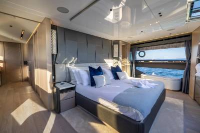 Luxurious yacht bedroom offers stunning ocean views through a large picture window and a circular porthole.