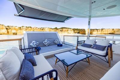 Relax on the luxurious deck of a yacht with stunning views of golden cliffs and turquoise waters.