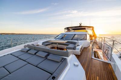 Golden hour illuminates the luxurious deck of a yacht as it cruises across the calm sea.