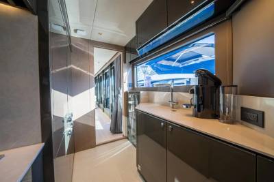 A sleek galley kitchen with a coffee machine and ample counter space offers a view of the bright blue waters outside.