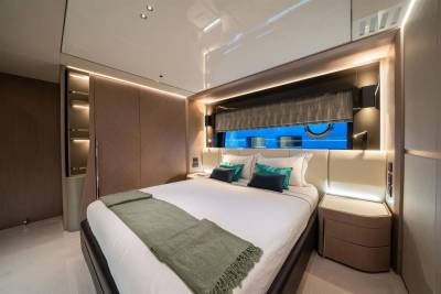 Luxurious yacht cabin features a plush bed, ambient lighting, and a porthole window offering a glimpse of the deep blue sea.