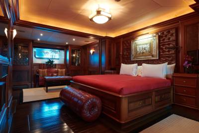 Luxurious wood paneling and rich red accents create an opulent atmosphere in this elegant yacht bedroom.
