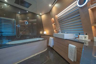 Luxurious modern bathroom features a sleek bathtub, a floating sink, and ambient blue lighting for a spa-like retreat.
