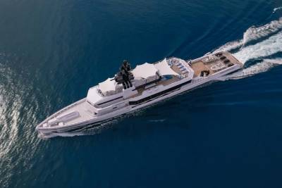A sleek white superyacht glides through the deep blue ocean, leaving a foamy wake behind.
