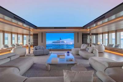 This luxurious yacht interior features a massive screen displaying a serene ocean view, complemented by plush seating and ambient lighting.