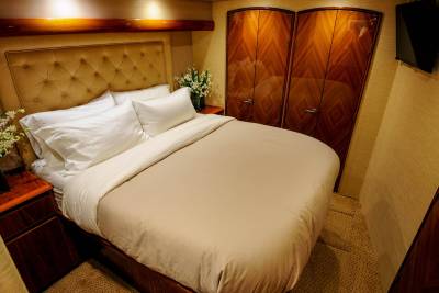 Luxurious cabin accommodations feature a plush bed, elegant wood cabinetry, and a wall-mounted television for ultimate comfort.