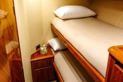 Bunk beds with crisp white pillows offer a cozy retreat within the luxurious, wood-paneled cabin of a yacht.