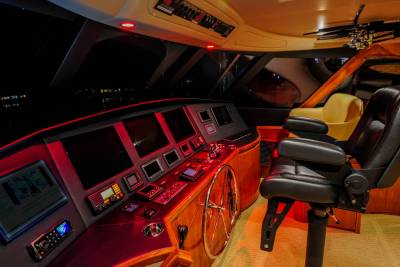 The luxurious yacht bridge glows with red ambient light, showcasing advanced navigation screens and a comfortable captain's chair.