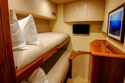 Luxurious bunk beds offer a cozy retreat aboard this elegant yacht, complete with a flat-screen TV and nautical artwork.