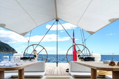 Enjoy a luxurious al fresco dining experience on deck with stunning ocean views and a backdrop of lush green hills.