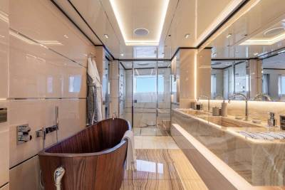 Luxurious yacht bathroom features a wooden soaking tub, a glass-enclosed shower, and a marble double vanity with sleek chrome fixtures.