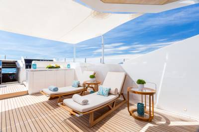 Relax on plush loungers on a sun-drenched yacht deck, surrounded by the azure sky and sparkling sea.