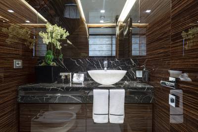 A luxurious bathroom features a marble countertop, a vessel sink, and rich wood-paneled walls.