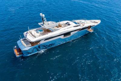 A luxurious yacht with a striking dragon graphic glides through the deep blue ocean.