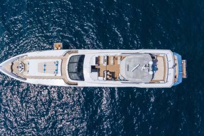 A luxurious yacht glides across the sparkling blue ocean, its decks adorned with comfortable seating and sun loungers.