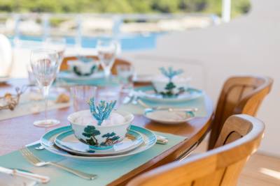 A beautifully set table awaits a delightful meal aboard a yacht, with the ocean as a stunning backdrop.